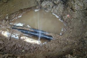 Water spraying from a one eighth inch underground pipe leak