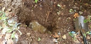 Excavated underground water pipe leak exposed in soil for repair