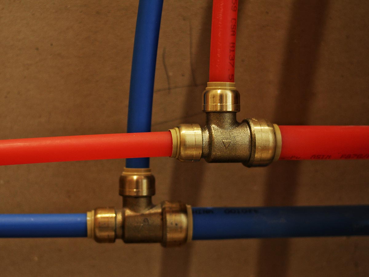 Red and blue PEX water lines joined with brass fittings