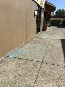 Commercial sidewalk showing the located leak and copper pipe