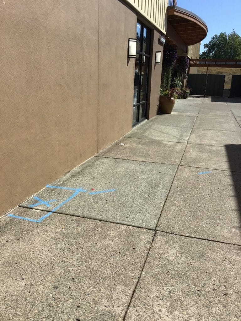 Commercial sidewalk with blue markings showing the location of an underground water pipe leak
