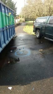 Blue paint circles on wet asphalt driveway marking the underground leak