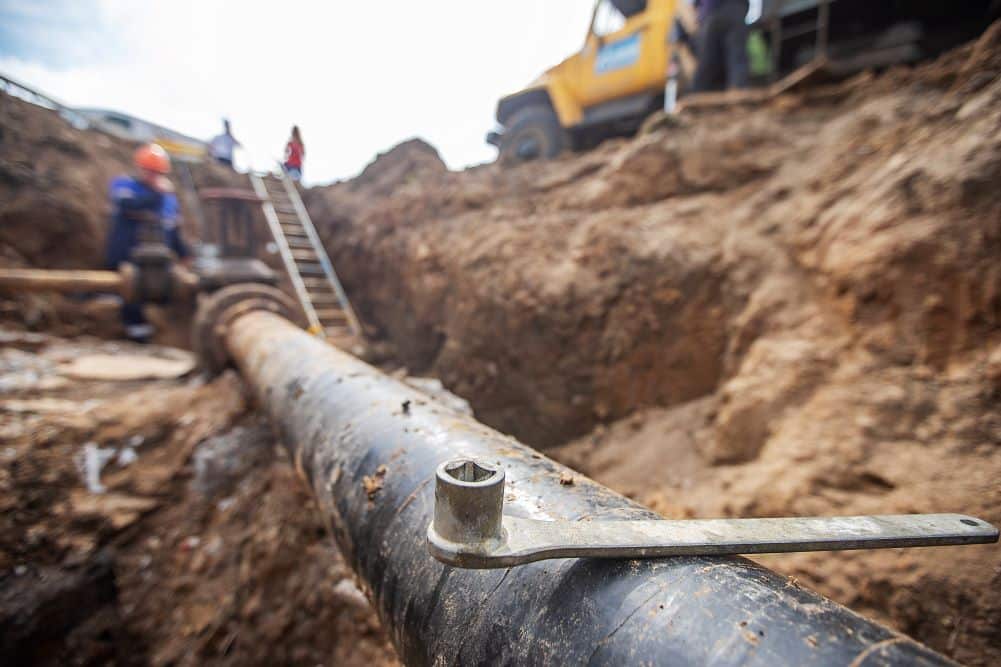 Workers excavating a deep trench to repair an underground water pipe
