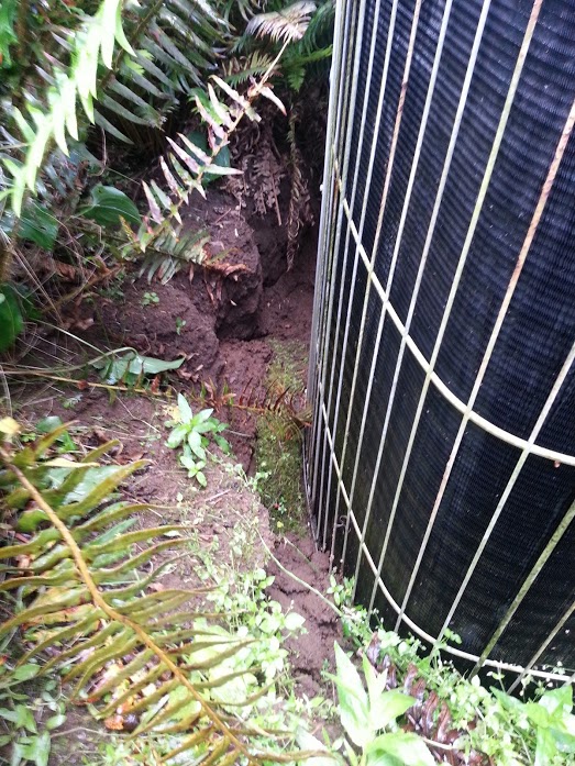 Excavated area beside a heat pump where a leak caused ground damage