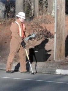Technician using leak detection equipment on a paved surface
